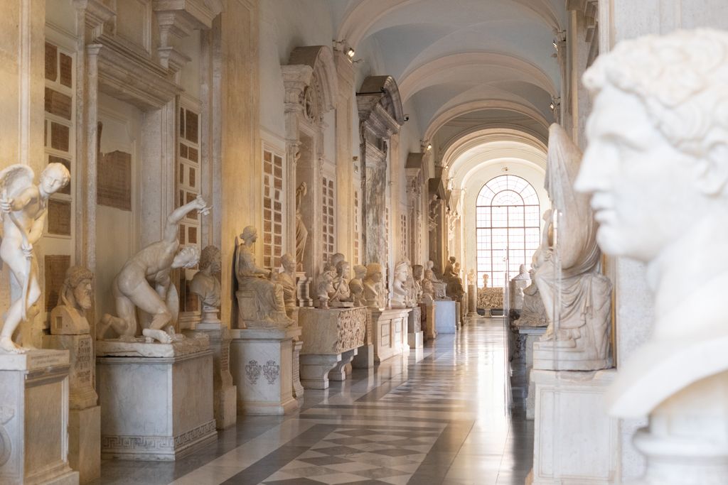 Elegant museum hallway with classical sculptures, showcasing Renaissance architecture and art.