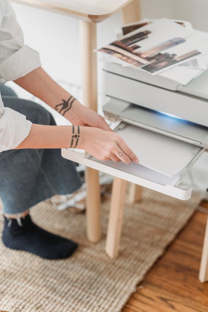 From above of crop anonymous female photographer with tattoo preparing paper for printing photos at home